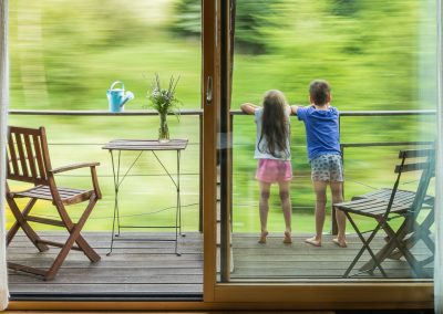 Deux enfant au balcon d'une maison avec le paysage qui défile
