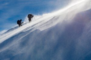 Deux skieurs de randonnée dans la tempête de vent face au soleil