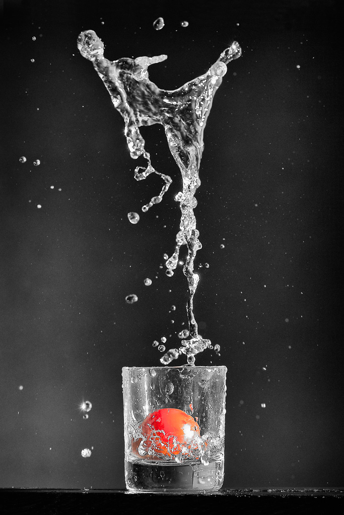 Eau jaillissante d'un verre contenant une tomate cerise
