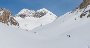 Deux skieurs de randonnée remontant un large vallon de neige