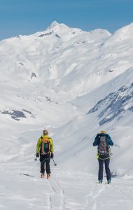 Deux skieurs de dos devant un vallon de neige