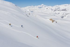 Trois skieurs dans la poudreuse devant le Mont Blanc